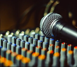 Microphone on top of an audio mixing console with blurred lights in the background