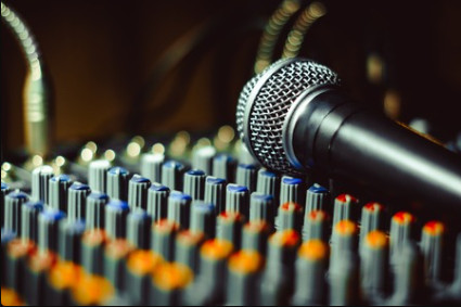 Microphone on top of an audio mixing console with blurred lights in the background