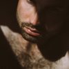 man with facial hair ooking down with shadow on face