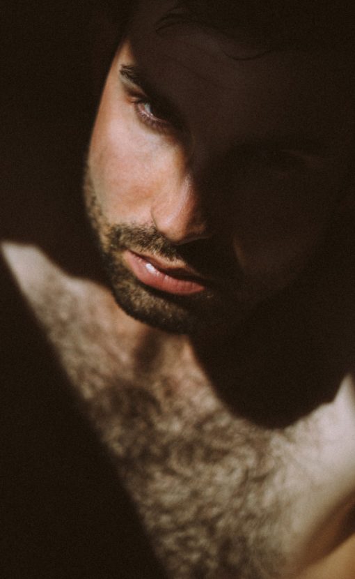 man with facial hair ooking down with shadow on face