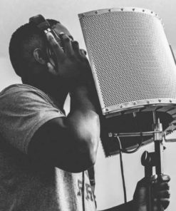 Muscular black man recording his voice for music in a studio