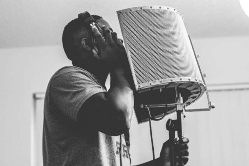 Muscular black man recording his voice for music in a studio