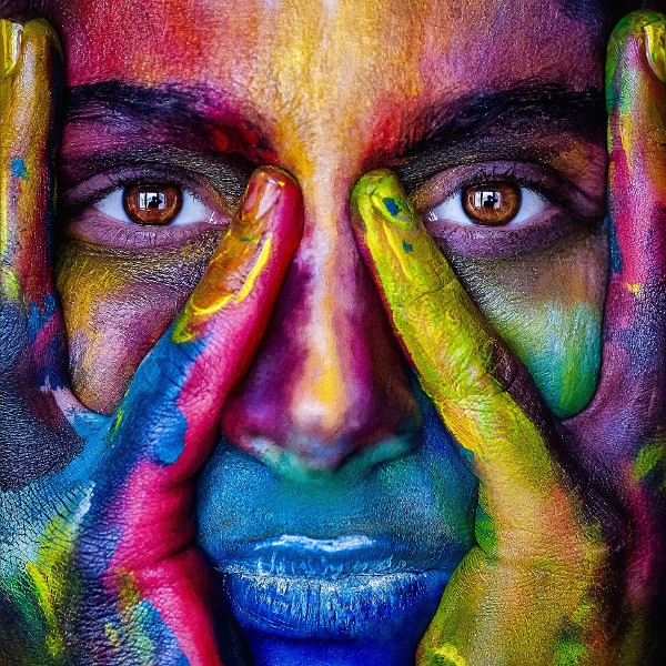 Woman holding face covered in vibrant rainbow of colors