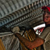 Hard-working man working on industrial building, with red hat, t-shirt, covered in dirt, gloves, harness