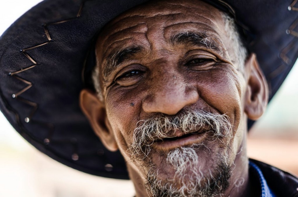 wrinkly smiling man with a cowboy hat on,